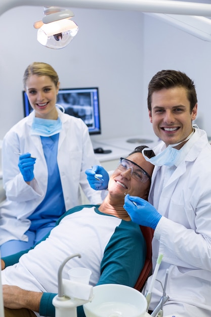 Portrait of dentists examining a male patient with tools