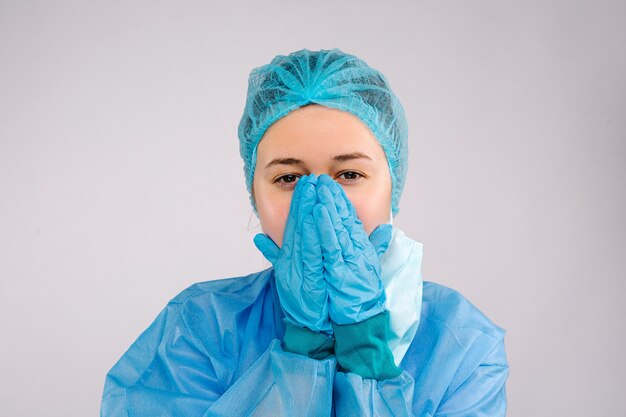 Portrait of depressed female doctor in a medical uniform on a gray isolated background