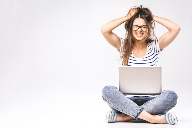 Portrait of depressed woman in casual sitting on floor in lotus pose and holding laptop