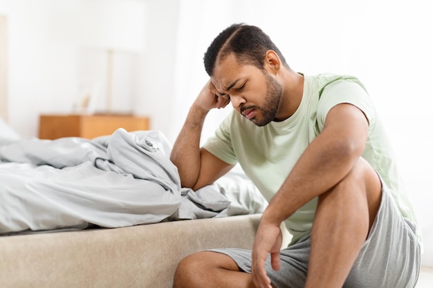 Portrait of depressed young black man sitting on floor