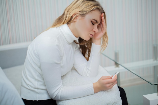 Portrait of desperate young woman holding pregnancy test stick