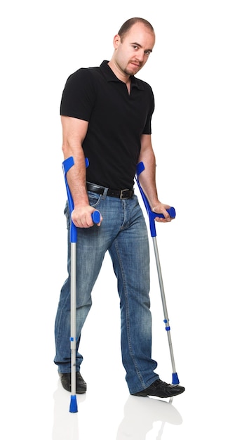 Photo portrait of disabled man walking with crutches against white background