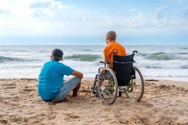 海を眺めている友人と一緒にビーチで車椅子に座っている障害者の肖像画