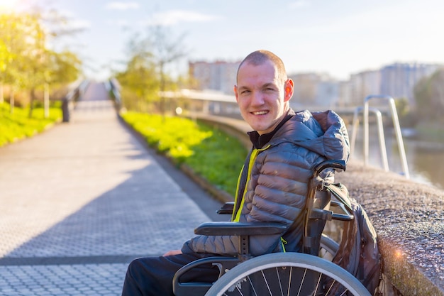 Portrait of a disabled person in a wheelchair by a river in the city sunset