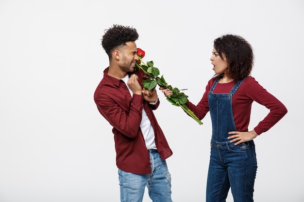 Portrait of a disappointed young woman holding red rose while angry on her boyfriend.