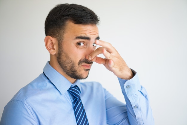 Photo portrait of disgusted clerk pinching nose