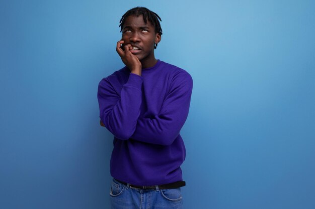 Portrait of distressed african young adult in jeans isolated on plain background