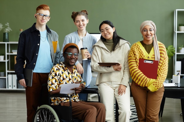 Photo portrait of diverse creative team looking at camera with cheerful smiles while posing in office whee