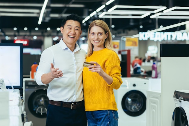 Portrait of diverse family couple asian man and woman shopping in supermarket electronics and