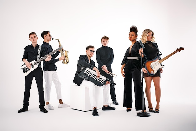 Portrait of diverse group of young people musical band playing with instruments isolated on white background