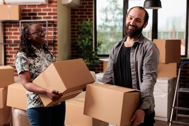 Portrait of diverse life partners posing with boxes on moving
day, unpacking furniture and things to decorate rented apartment
flat. using cargo storage to settle in property bought on
loan.