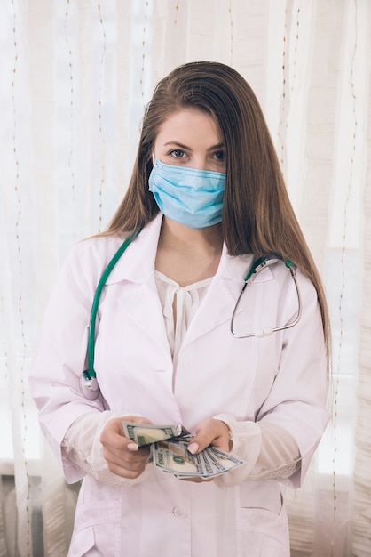 Portrait of a doctor counting dollar banknotes