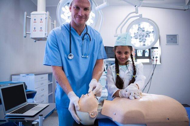 Portrait of doctor and girl examining a dummy