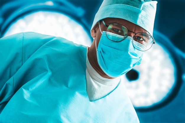 Portrait of a doctor in a mask on a background of surgical lamps. Medicine concept. 