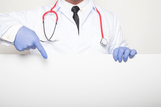 Portrait of a doctor pointing at blank poster with finger