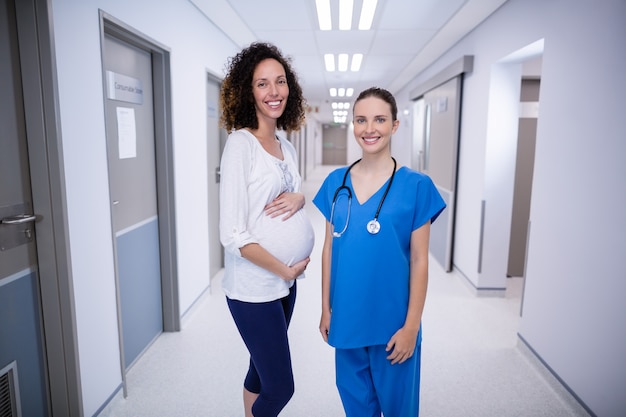 Portrait of doctor and pregnant womans standing in corridor