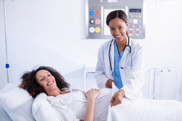 Photo portrait of doctor putting blanket on pregnant woman