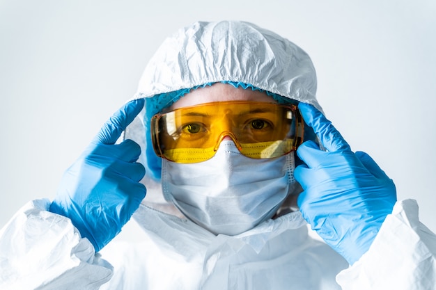 Portrait of a doctor putting on a mask and blue uniform. isolated on white background. 2019-nCoV pandemic, Novel Chinese Coronavirus, Wuhan Coronavirus concept.