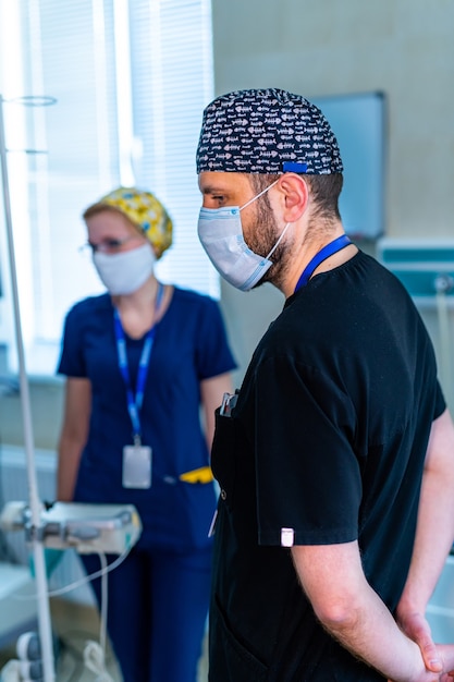 Portrait of doctor in scrubs. Background with medical office. Doctor in medical mask and scrubs. Close up shot.