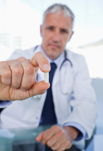 Portrait of a doctor showing a pill