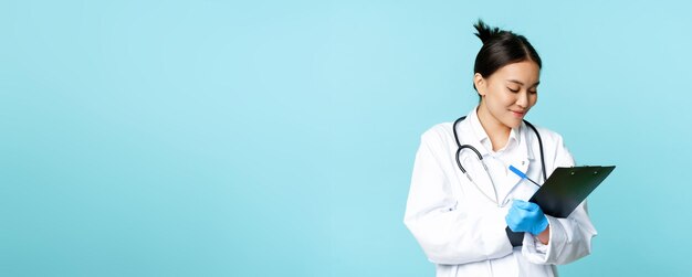 Portrait of doctor standing against blue background