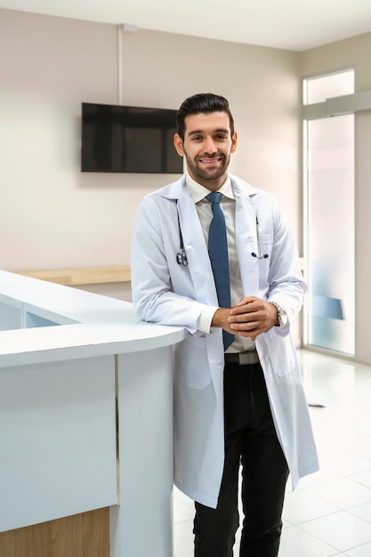 Portrait of doctor wearing white coat standing and smiling In hospital