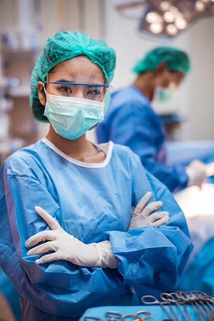 Foto ritratto di un medico con le braccia incrociate in piedi in sala operatoria