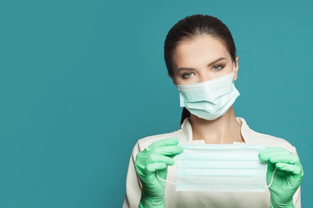 Portrait of doctor with protective medical face mask on blue background Medicine concept