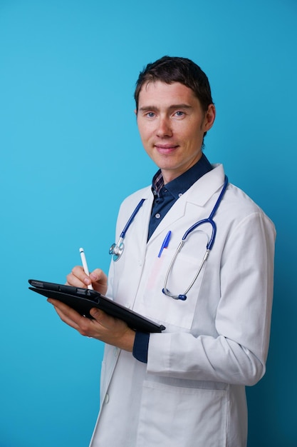青い背景に聴診器とタブレットコンピューターを手に医師の肖像画