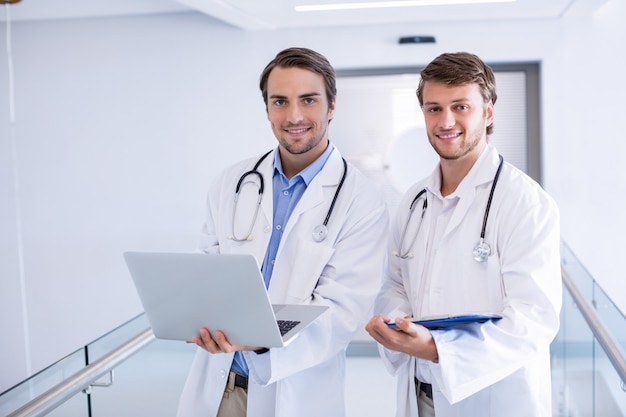 Portrait of doctors using laptop in corridor