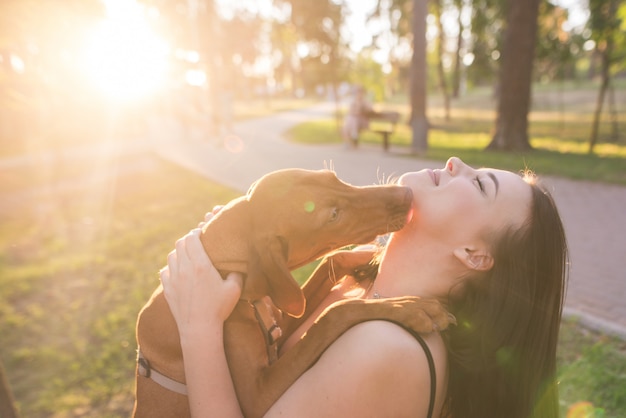 Portrait of a dog kissing a happy woman in a park