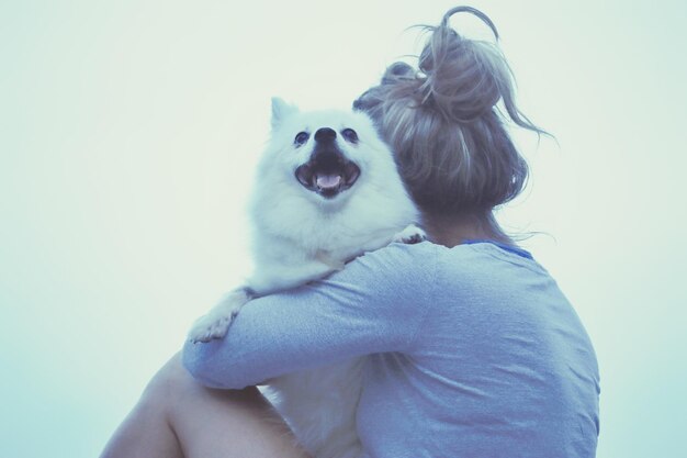 Foto ritratto di un cane con una donna contro il cielo