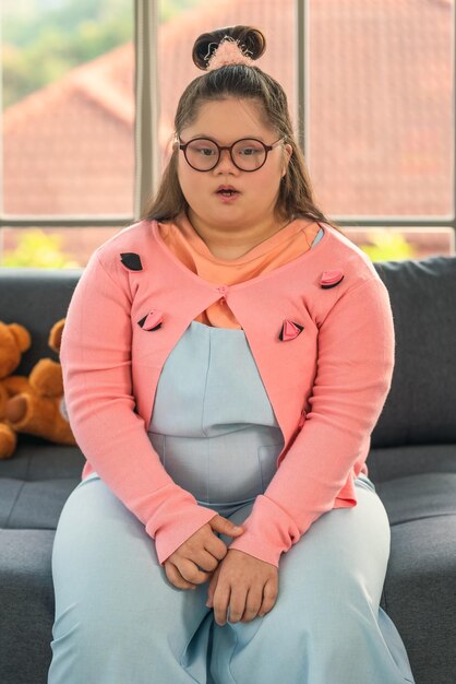 Photo portrait of down syndrome teenager girl sitting on fosa at home