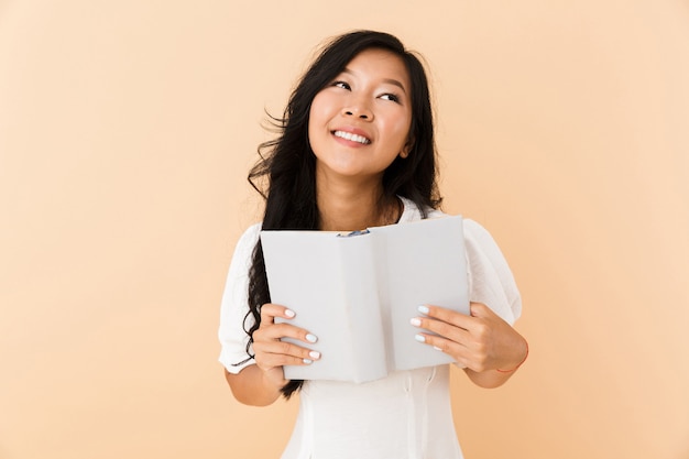 Photo portrait of a dreamy asian girl isolated over beige