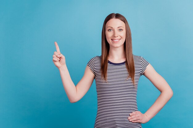 Portrait of dreamy cheerful girl direct finger empty space present novelty on blue background