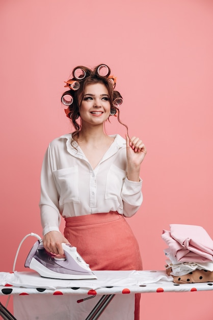 Portrait of dreamy housewife while ironing clean clothes on ironing board