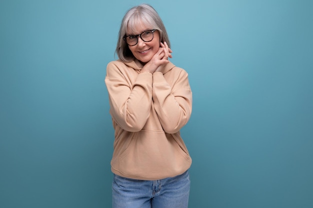 Portrait of a dreamy mature woman with gray hair in a casual look on a studio background with copy