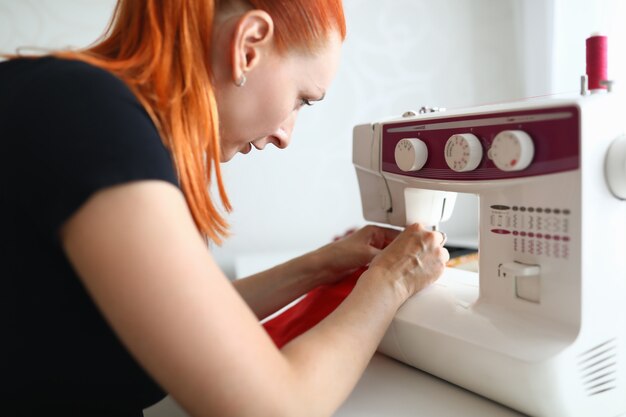 Portrait of dressmaker woman working on white sewing machine