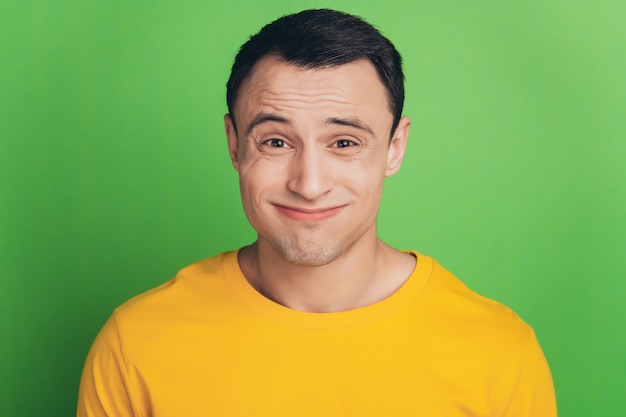 Portrait of dumb unsure guy shrug shoulders clueless face on green background