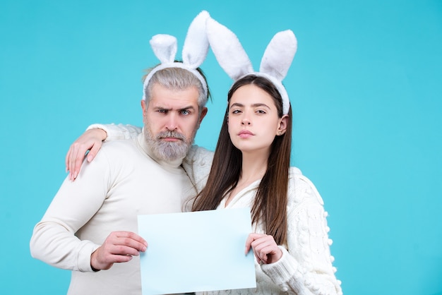 Portrait of easter couple bunny woman and bunny man hold paper for text funny couple dressed in cost...