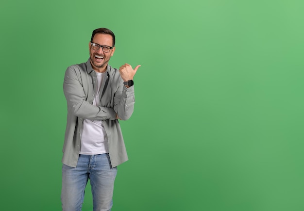 Портрет экстатического продавца, представляющего пустое пространство для маркетинга на изолированном зеленом фоне