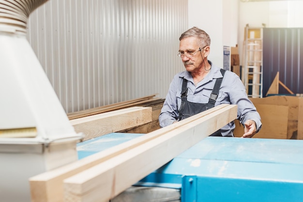 Portrait of an elderly carpenter or carpenter working with wooden boards in a carpenter39s workshop