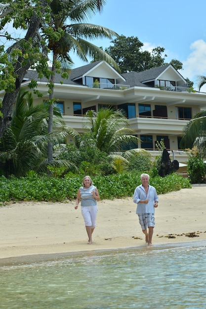 Portrait of elderly couple running on tropical beach