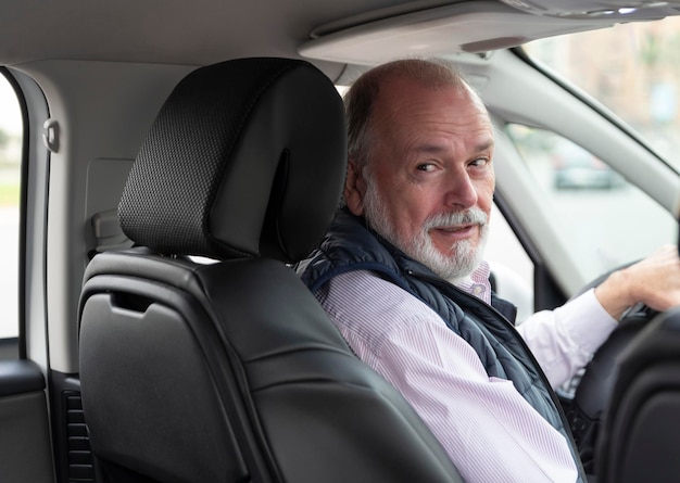 Portrait of an elderly driver in car or taxi