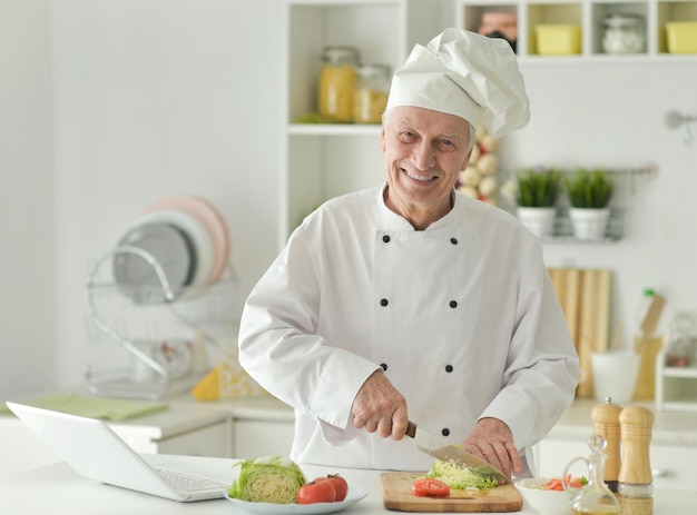 Portrait of a elderly male chef cooking salad