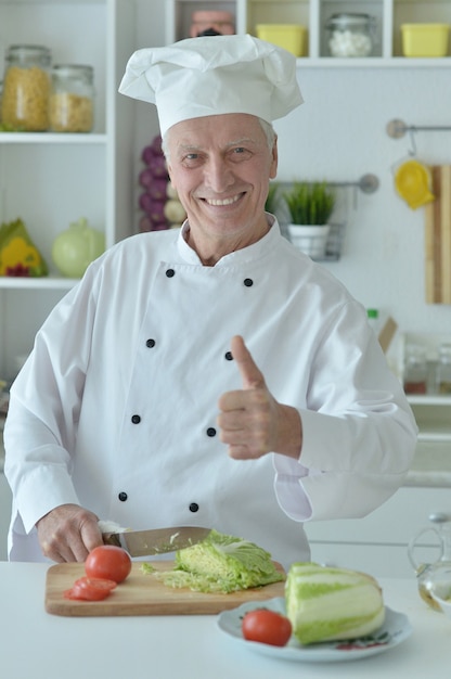 Portrait of a elderly male chef cooking salad