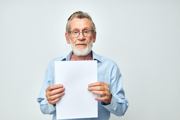 Portrait elderly man in a blue shirt and glasses a white sheet of paper unaltered