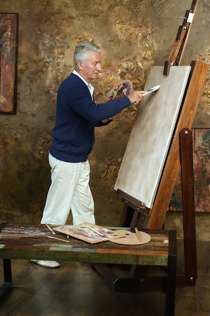 Photo portrait of elderly man painting with easel