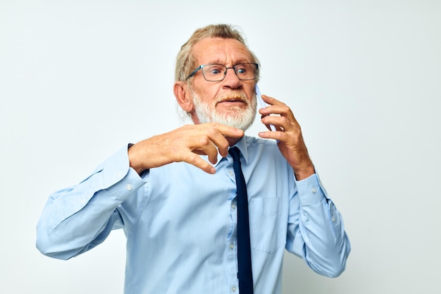 Portrait elderly man in a shirt with a tie talking on the phone light background