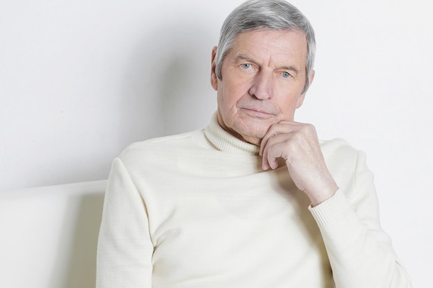 portrait of an elderly man sitting in a chair.isolated on white wall